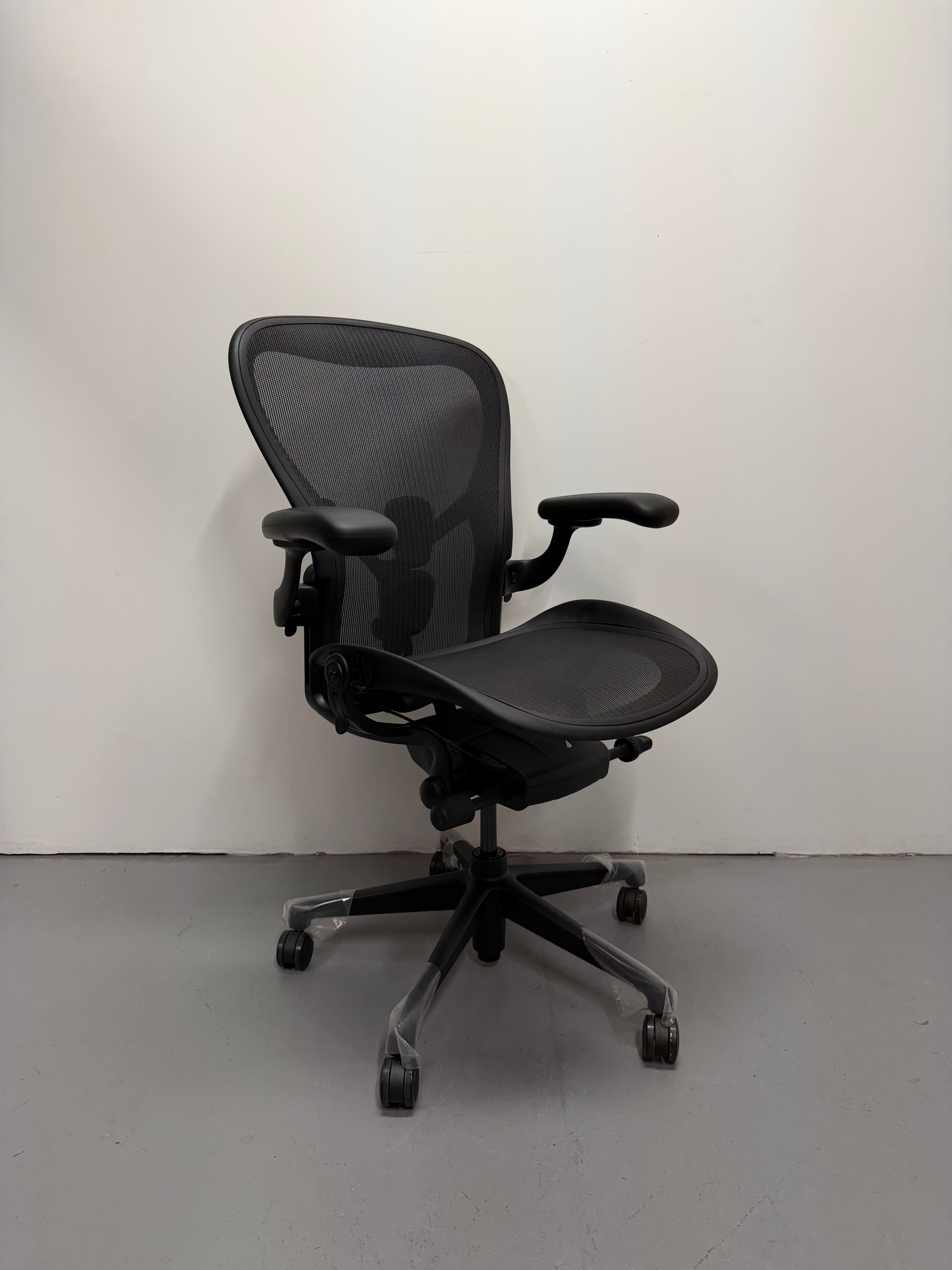 Black office chair on a gray floor with a white wall background