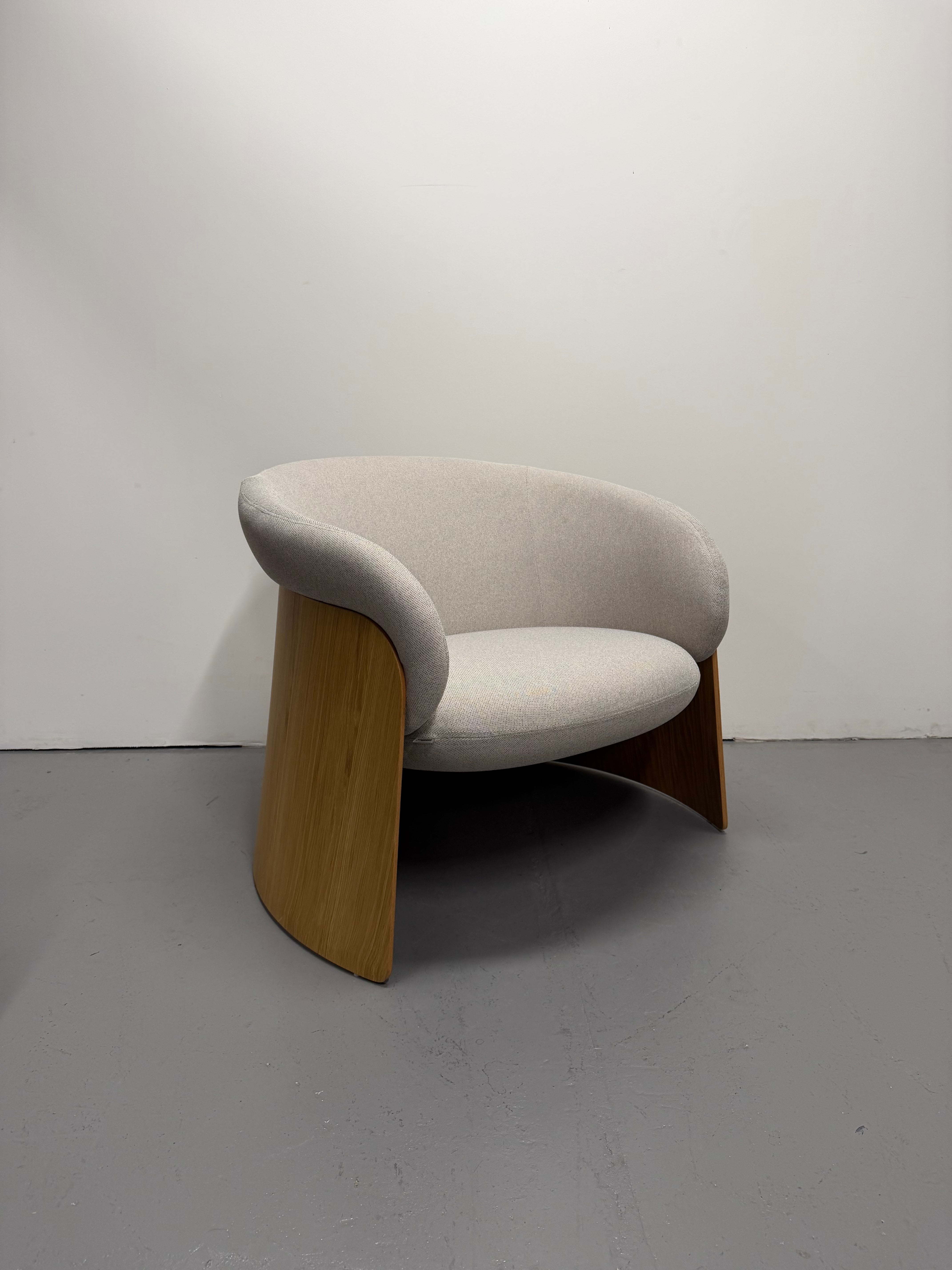 Modern chair with curved design and wooden legs on a plain background