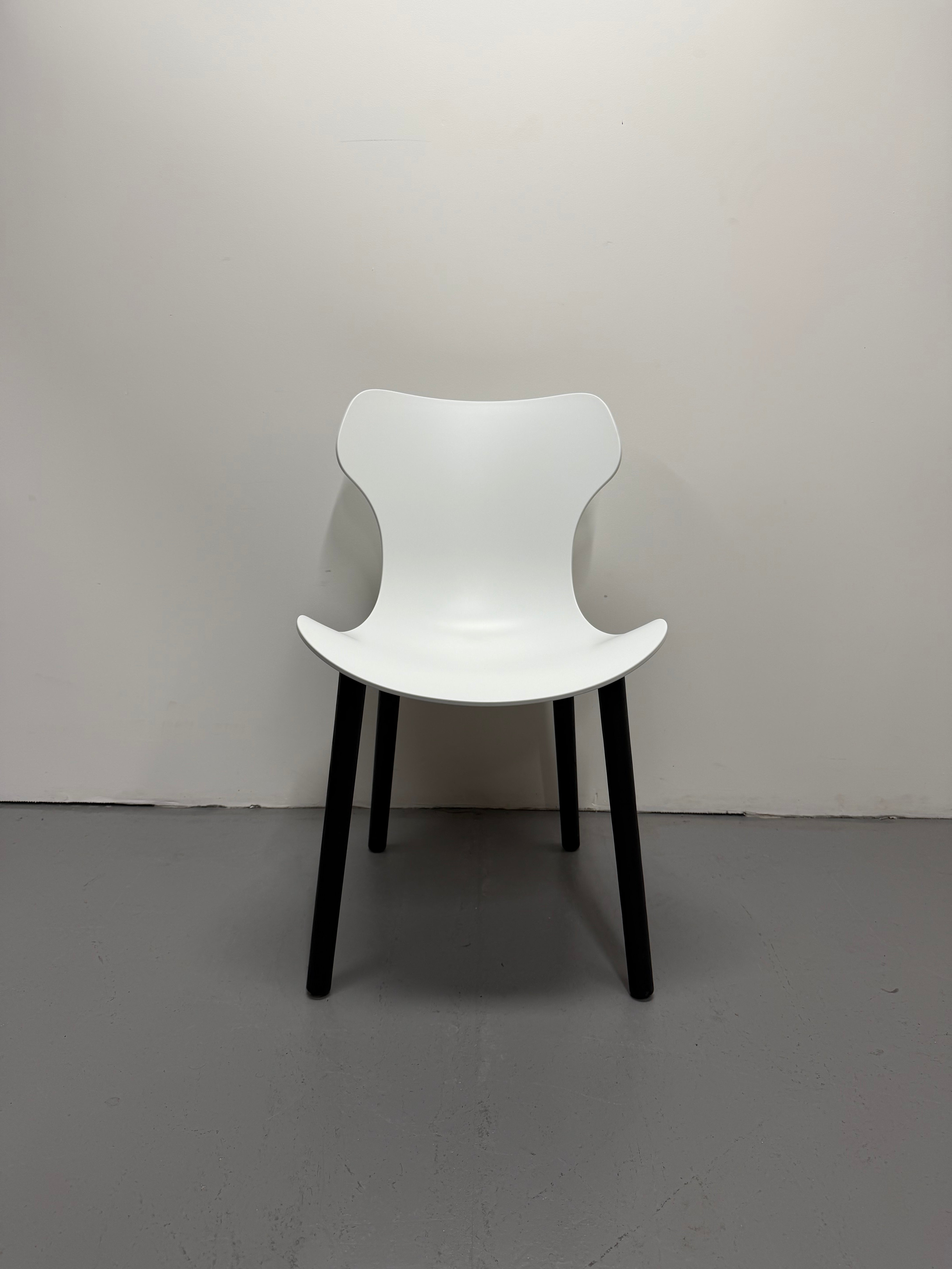 White chair with black legs on a plain gray floor and background